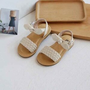 Girls beige flat sandals with woven front strap and bow ankle closure
